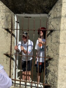 Two people inside a prison holding steel bars