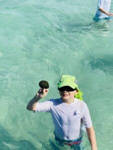 A small boy wearing sunglasses and playing in water