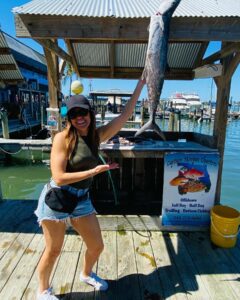 A woman holding a long fish on deck